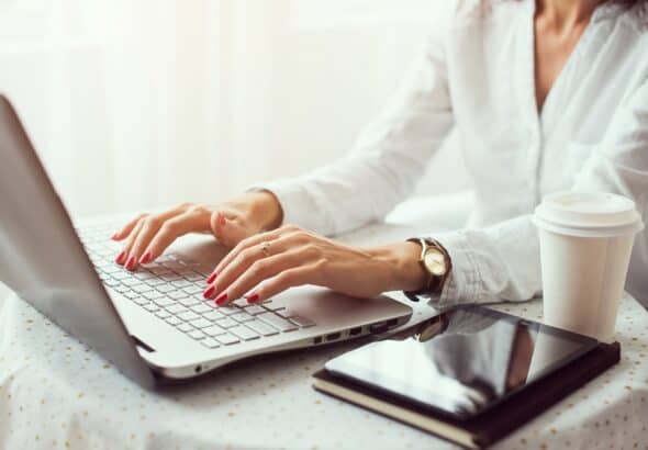 Woman working in home office hand on keyboard close up.
