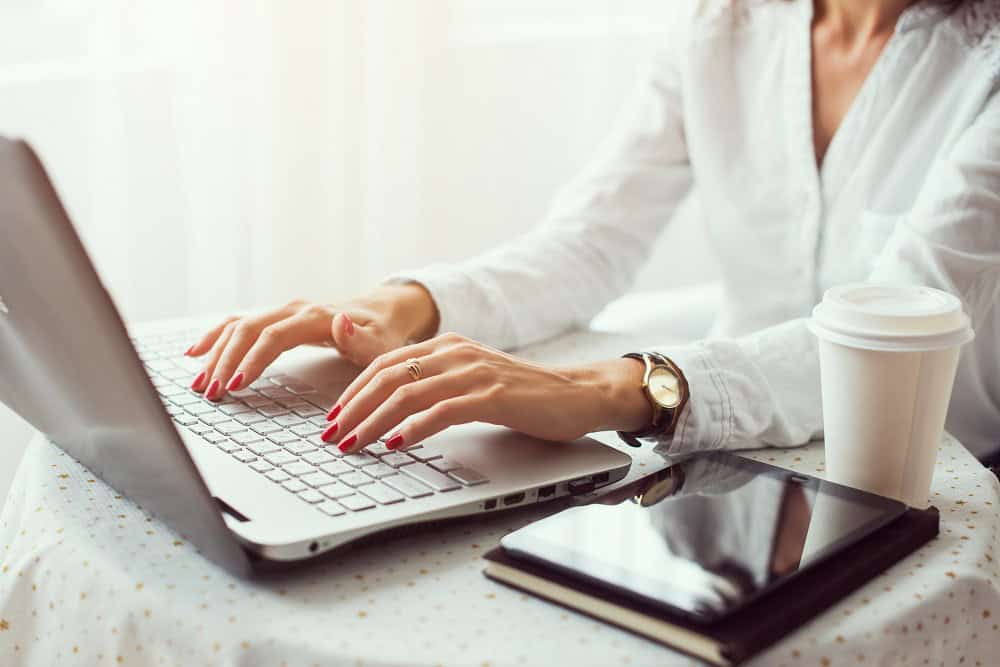 Woman working in home office hand on keyboard close up.